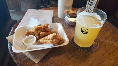Frickles (fried pickles) and a pint of beer on a wooden pub table