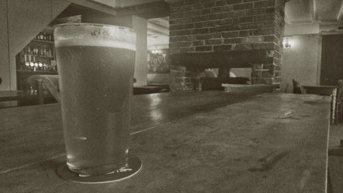 A pint of beer on a wooden table in a pub